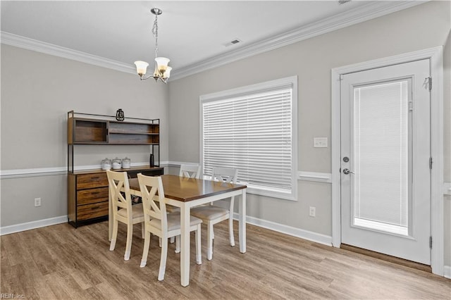 dining space with a chandelier, visible vents, light wood-type flooring, and ornamental molding