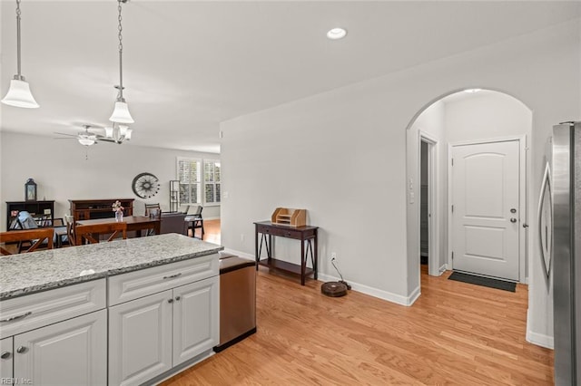 kitchen featuring light wood-style floors, ceiling fan, white cabinetry, arched walkways, and freestanding refrigerator
