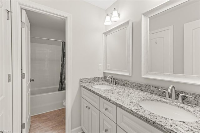 bathroom featuring double vanity, shower / tub combo, toilet, and a sink