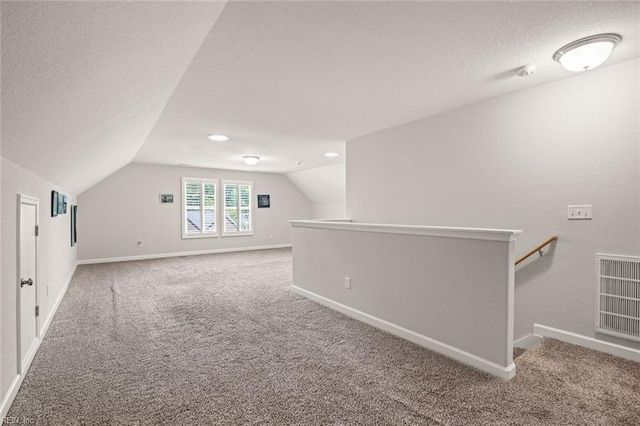 additional living space featuring lofted ceiling, a textured ceiling, visible vents, and carpet flooring