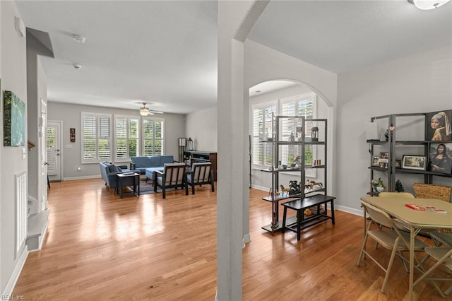 living room with ceiling fan, baseboards, light wood-style flooring, and arched walkways