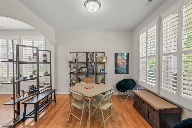 office featuring arched walkways, visible vents, baseboards, and light wood-style floors