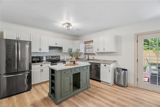 kitchen with stainless steel appliances, under cabinet range hood, a kitchen island, a sink, and white cabinetry