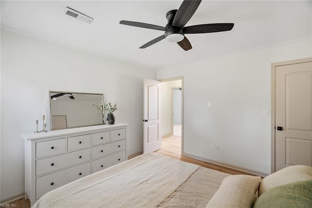 bedroom featuring baseboards, visible vents, ceiling fan, and light wood-style flooring