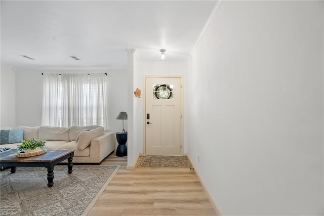 entryway with ornamental molding, visible vents, baseboards, and light wood-style floors