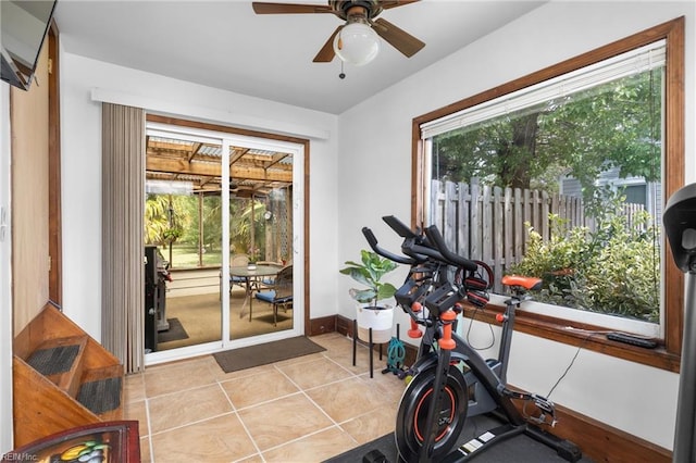 workout room with light tile patterned floors, a ceiling fan, and baseboards