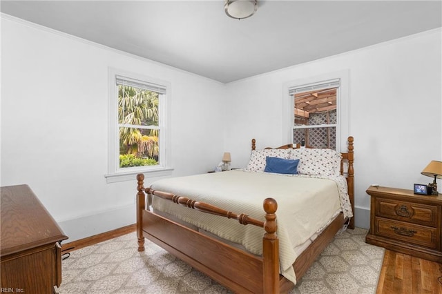bedroom with light wood-style floors, crown molding, and baseboards