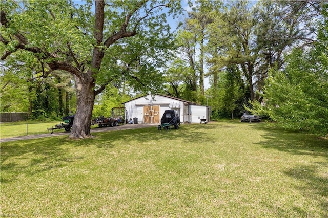 view of yard with an outdoor structure, a detached garage, and fence