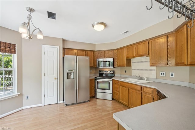 kitchen with visible vents, stainless steel appliances, brown cabinets, and a sink