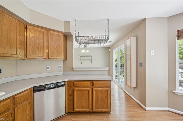 kitchen featuring stainless steel dishwasher, light countertops, a peninsula, and light wood-style floors