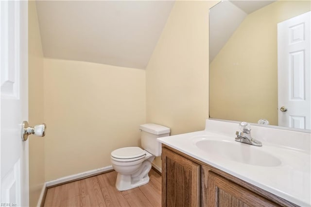 half bathroom featuring baseboards, toilet, vaulted ceiling, wood finished floors, and vanity