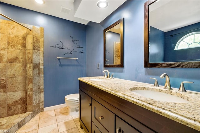 full bathroom with double vanity, a tile shower, toilet, and a sink