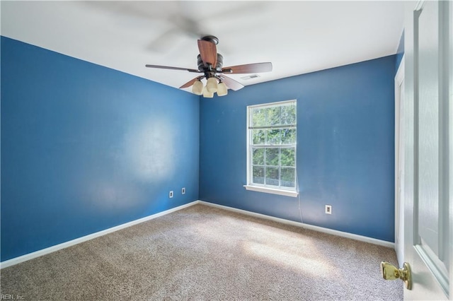 carpeted spare room with ceiling fan and baseboards