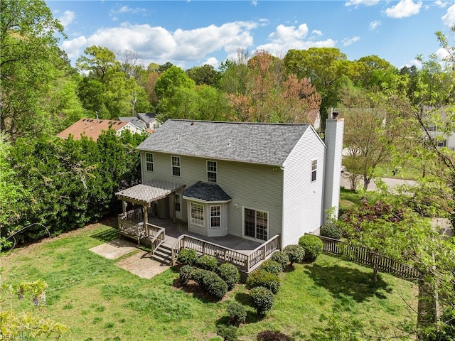 rear view of house featuring a chimney, fence, a wooden deck, and a yard