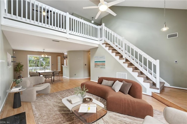 living room featuring wood finished floors, high vaulted ceiling, and stairs
