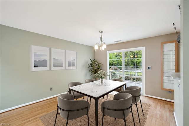 dining space featuring visible vents, baseboards, a chandelier, and light wood-type flooring