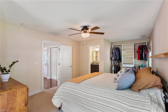 carpeted bedroom with a closet, ceiling fan, ensuite bath, visible vents, and baseboards