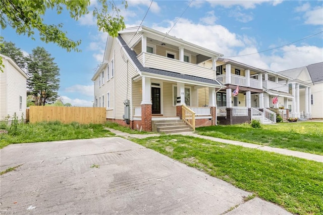 view of front of home with a front lawn, a balcony, covered porch, and fence
