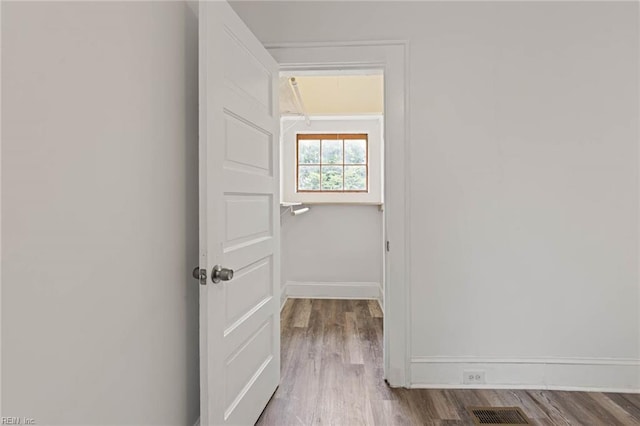 hall featuring visible vents, wood finished floors, and baseboards