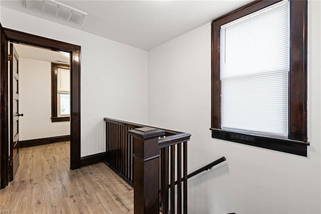 hall with plenty of natural light, an upstairs landing, light wood finished floors, baseboards, and visible vents