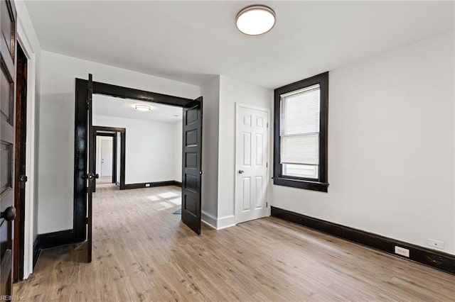 spare room featuring light wood finished floors and baseboards