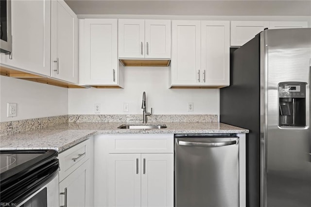 kitchen with white cabinetry, light stone counters, appliances with stainless steel finishes, and a sink