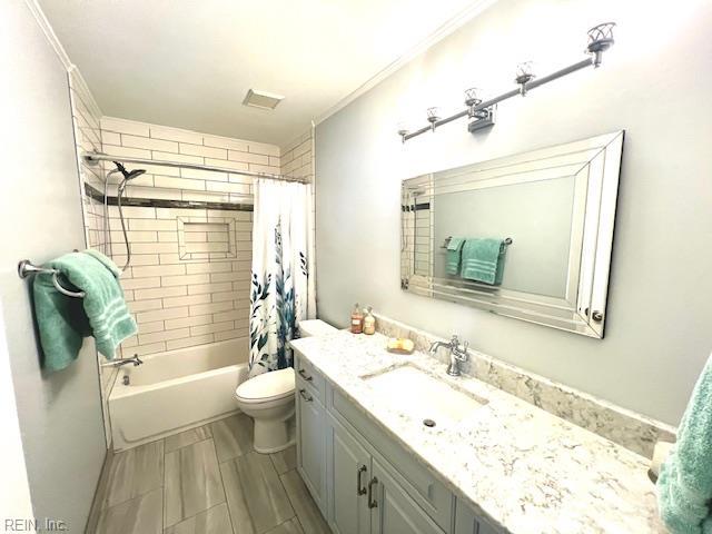 full bath featuring crown molding, toilet, shower / bathtub combination with curtain, and vanity