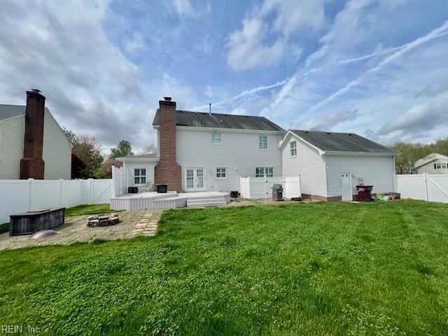 rear view of house featuring a fire pit, a patio, a fenced backyard, a chimney, and a yard