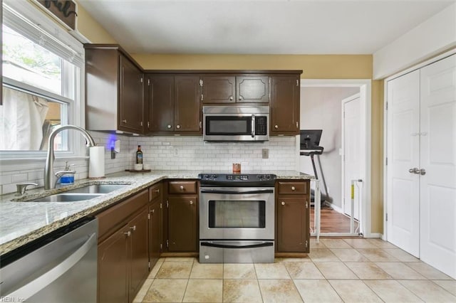 kitchen with dark brown cabinetry, a sink, stainless steel appliances, and decorative backsplash