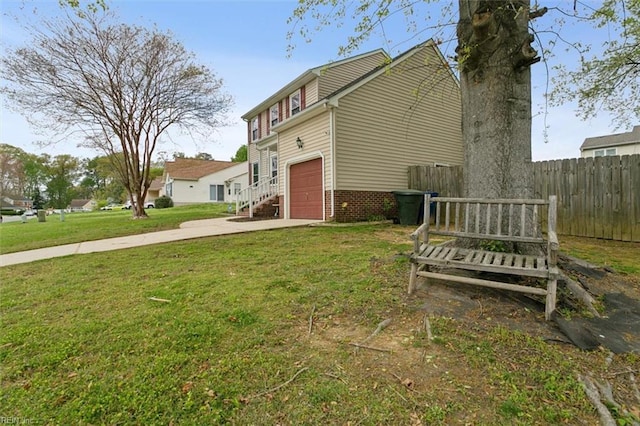 exterior space featuring concrete driveway, a yard, a garage, and fence