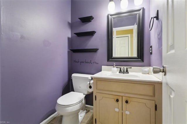 half bath featuring baseboards, tile patterned floors, toilet, and vanity