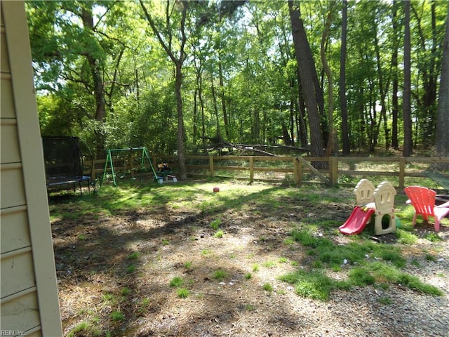 view of yard with a trampoline, a fenced backyard, and a playground