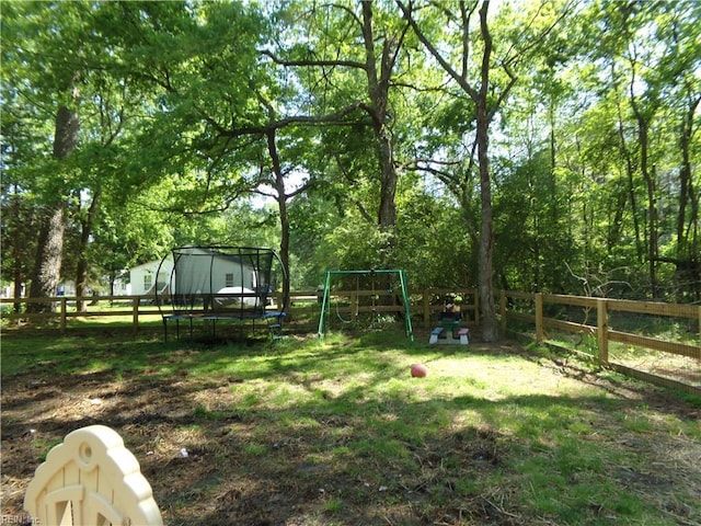 view of yard with a trampoline, a fenced backyard, and a playground