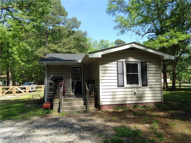 view of front of property with roof with shingles and fence
