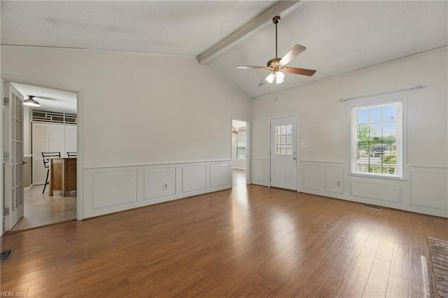 interior space featuring ceiling fan, vaulted ceiling with beams, a wainscoted wall, visible vents, and wood finished floors