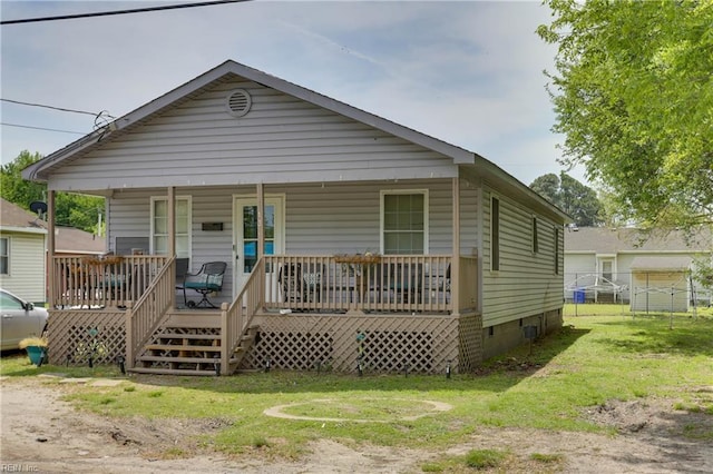 view of front facade with a front yard, crawl space, covered porch, and fence