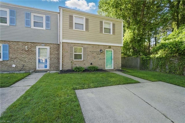townhome / multi-family property featuring brick siding, fence, and a front yard