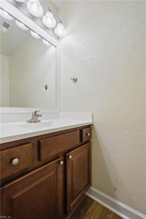 bathroom with baseboards, visible vents, wood finished floors, and vanity
