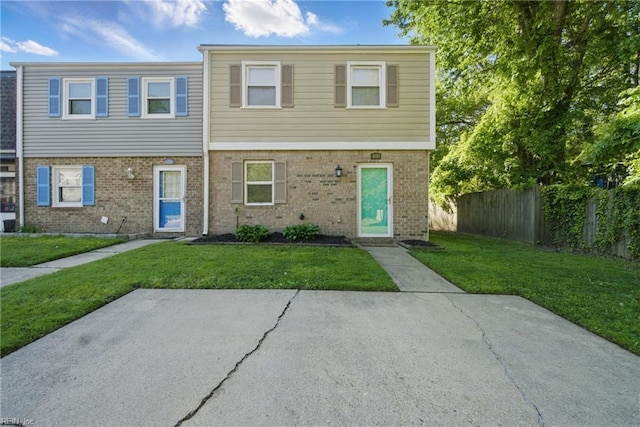 multi unit property featuring fence, a front yard, and brick siding