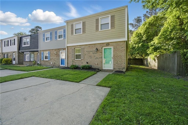 townhome / multi-family property featuring brick siding, a front lawn, and fence