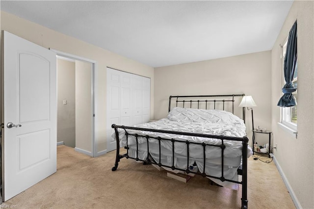 bedroom featuring a closet, light colored carpet, and baseboards