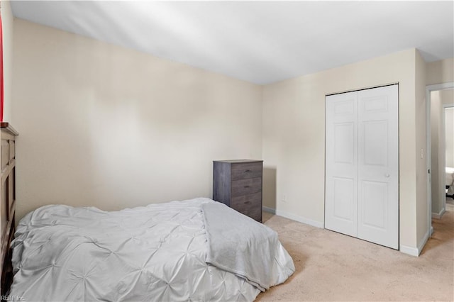 carpeted bedroom featuring baseboards and a closet