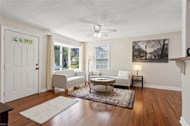 living room featuring baseboards, wood finished floors, a ceiling fan, and a textured ceiling