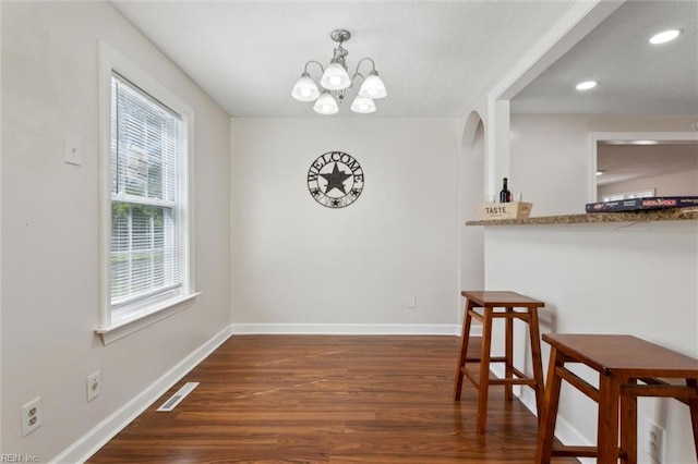dining room with baseboards, visible vents, wood finished floors, and a notable chandelier