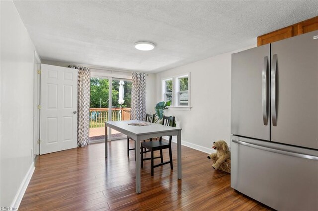 dining area with dark wood-type flooring, a textured ceiling, and baseboards