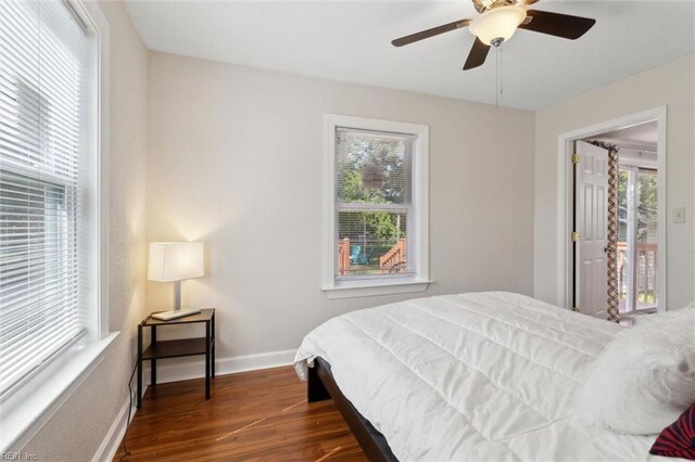 bedroom with baseboards, ceiling fan, dark wood-style flooring, and multiple windows