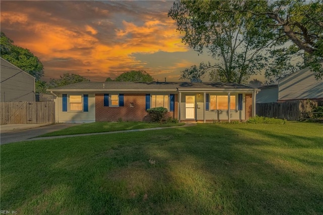 view of front facade featuring a lawn, brick siding, and fence