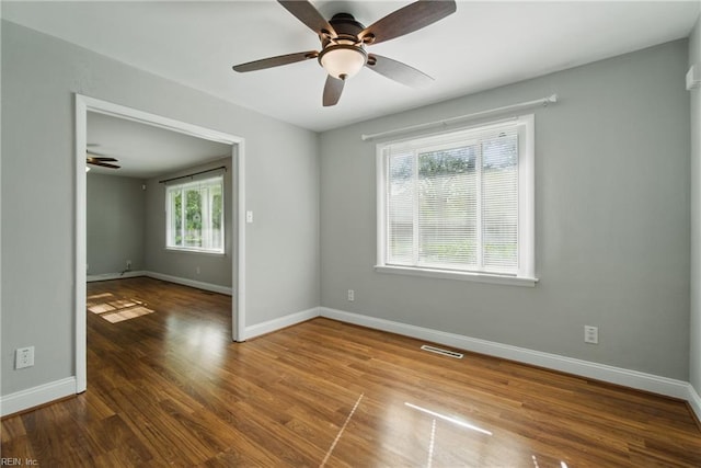unfurnished room with baseboards, visible vents, wood finished floors, and ceiling fan
