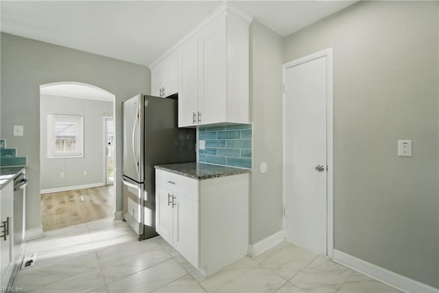 kitchen with stainless steel appliances, marble finish floor, white cabinetry, baseboards, and arched walkways