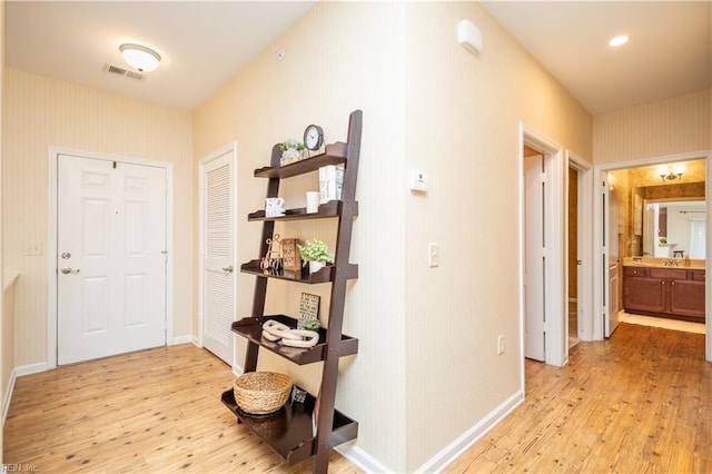 hallway with baseboards, visible vents, and light wood-style flooring